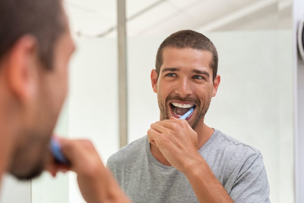 Man brushing his teeth in the mirror preventative dentistry dentist in Burlington North Carolina